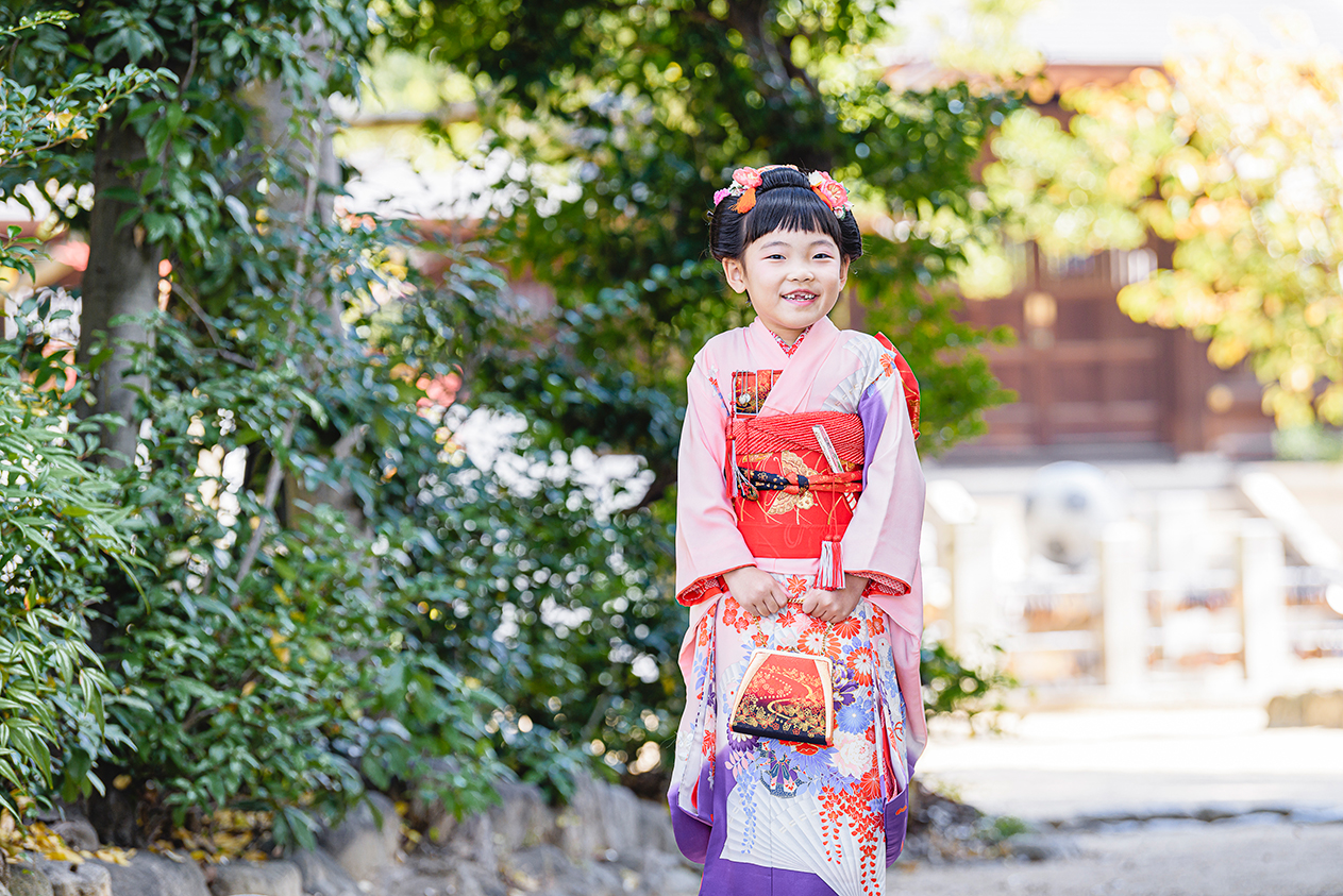石垣を背景に和傘を持つお子さま