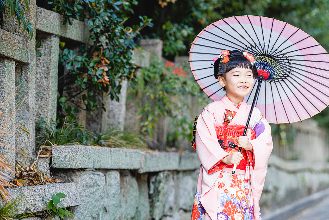 石垣の前で和傘を持ち笑うお子さま