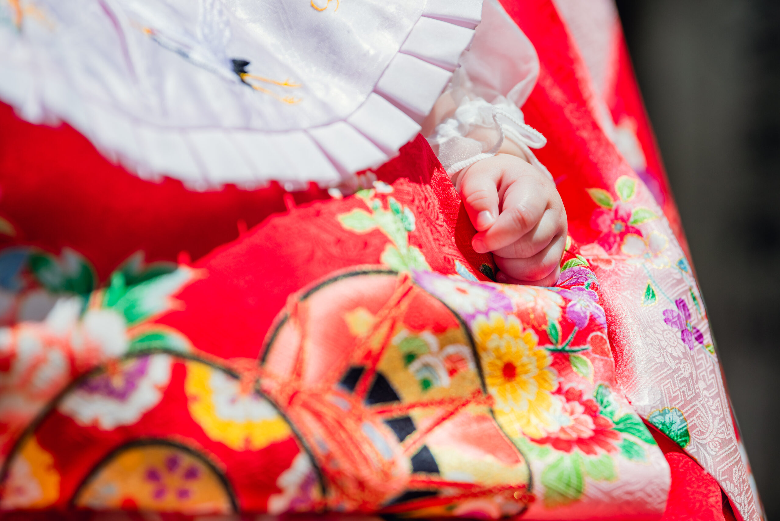 生田神社お宮参り|お祝い着のすきまからちょこんと顔を出す主役のお子さまの小さなお手て【Lighthouse Photo】