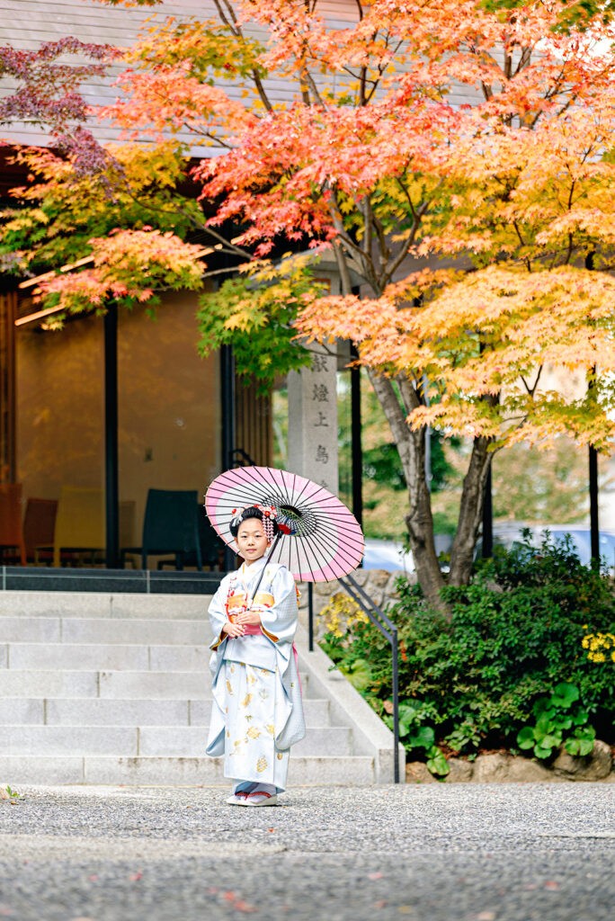 紅葉に包まれた芦屋神社の客殿前。晴れ着に日傘のお子さま